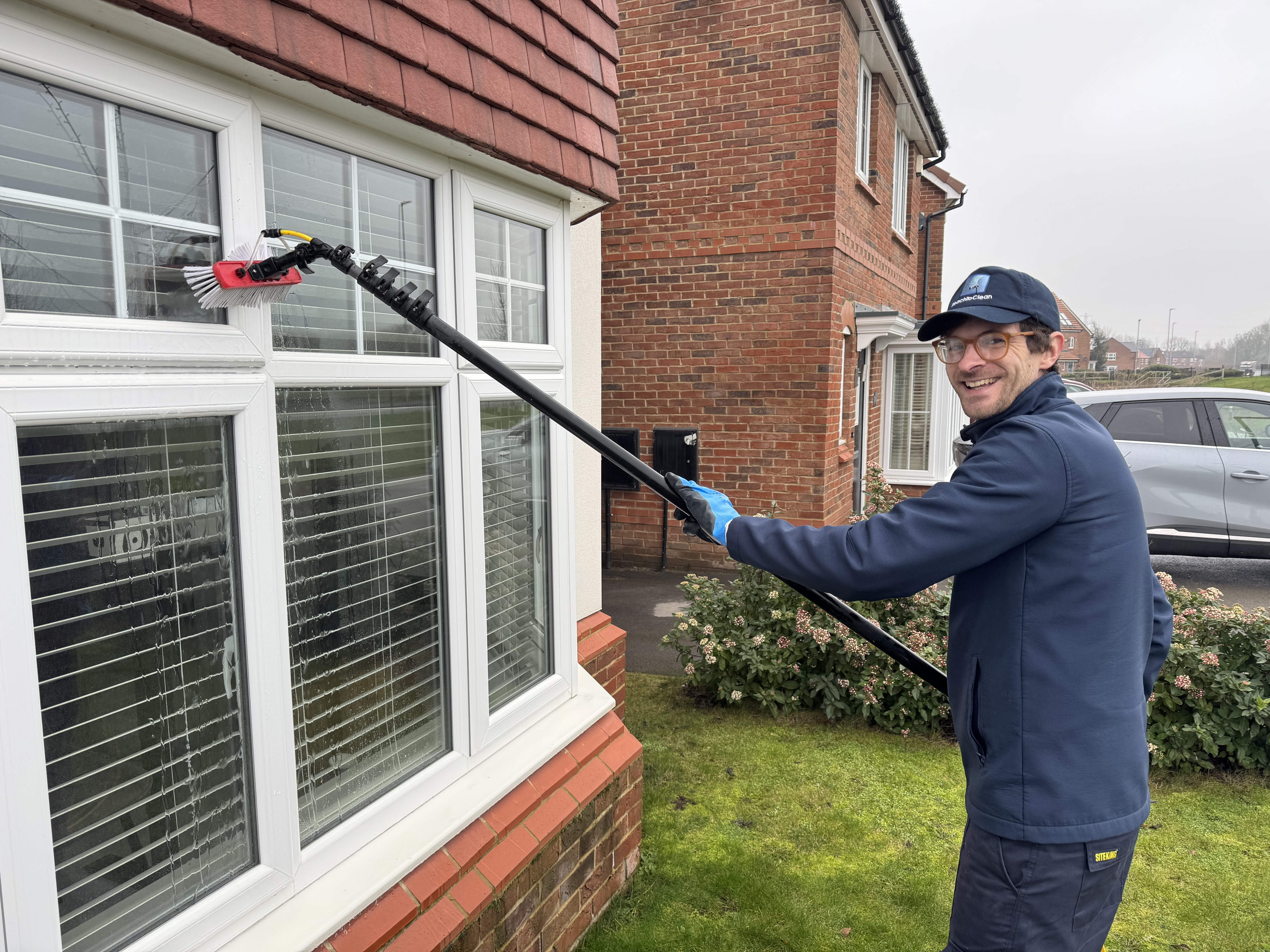 Reach To Clean team member cleaning windows with a pure water pole system at a Wakefield home